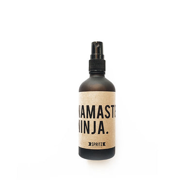 Front facing product shot of Namaste Ninja aromatherapy mist. Dark brown glass bottle with kraft paper label. Available for purchase on The Conservationist.  