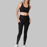 The Conservationist: Eco-friendly black leggings made out of post consumer recycled plastic. Front facing image of  black leggings with hands in deep side pocket. 