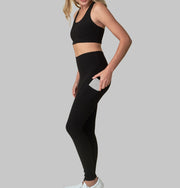 The Conservationist: Eco-friendly black leggings made out of post consumer recycled plastic. Front facing image of  black leggings with hand putting phone in deep side pocket. 
