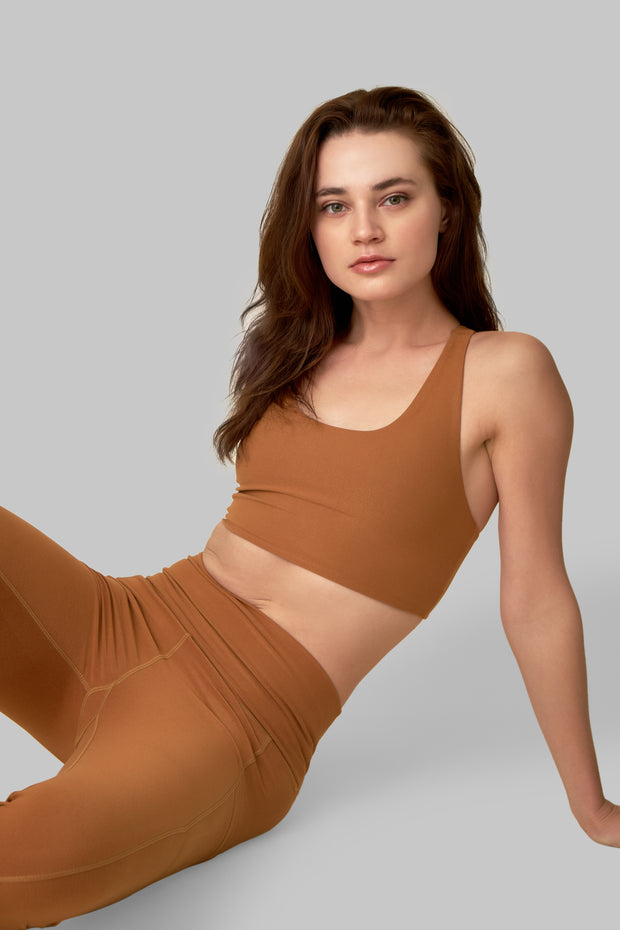 Front facing image of a rich turmeric colored eco-friendly yoga exercise top, made from post consumer recycled plastic. Available on The Conservationist. 