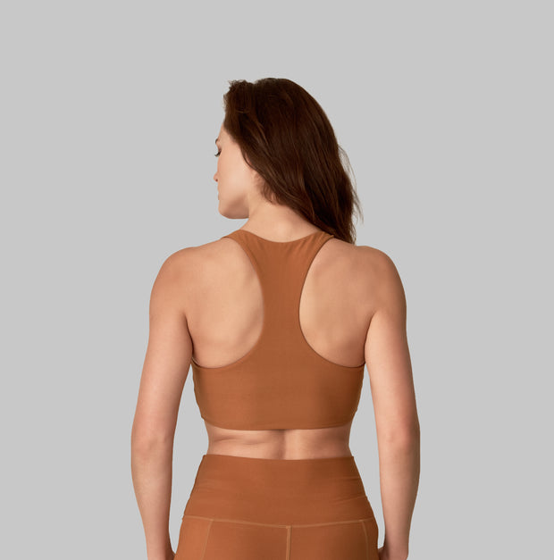 Back facing image of a rich turmeric colored eco-friendly yoga exercise top, made from post consumer recycled plastic. Available on The Conservationist. 