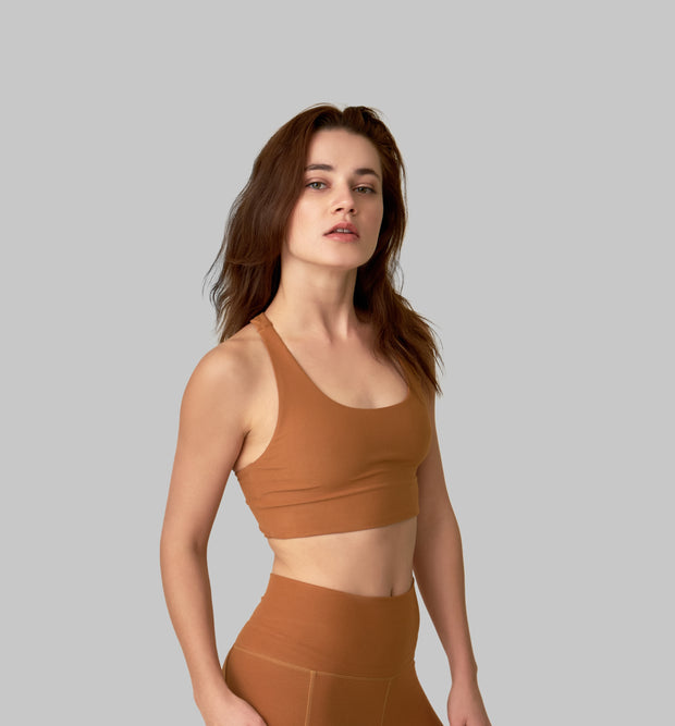 Side facing image of a rich turmeric colored eco-friendly yoga exercise top, made from post consumer recycled plastic. Available on The Conservationist. 